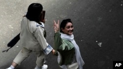 FILE - An Iranian woman without a mandatory headscarf, or hijab, flashes a victory sign as she walks at the old main bazaar of Tehran, Iran, June 13, 2024. 