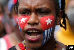 Seorang mahasiswa Papua dengan wajah dicat bendera "Bintang Kejora" meneriakkan slogan-slogan dalam unjuk rasa di depan Istana Kepresidenan di Jakarta, 28 Agustus 2019.