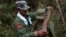 FILE - A rebel soldier of Myanmar National Democratic Alliance Army places a machine gun bullet belt around the neck of another soldier at a military base in Kokang region, March 10, 2015. 