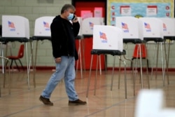 FILE - An election official talks on the phone near voting booths set up ahead of a 7th Congressional District special election, at Edmondson High School, in Baltimore, Maryland, April 27, 2020.