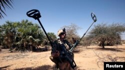A French soldier carries mine detection equipment to search for mines outside Gao, Mali, March 9 2013. 
