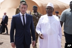 FILE - French President Emmanuel Macron, left, talks to Mali's President Ibrahim Boubacar Keita as they meet French soldiers of Operation Barkhane, France's largest overseas military operation, in northern Mali, May 19, 2017.