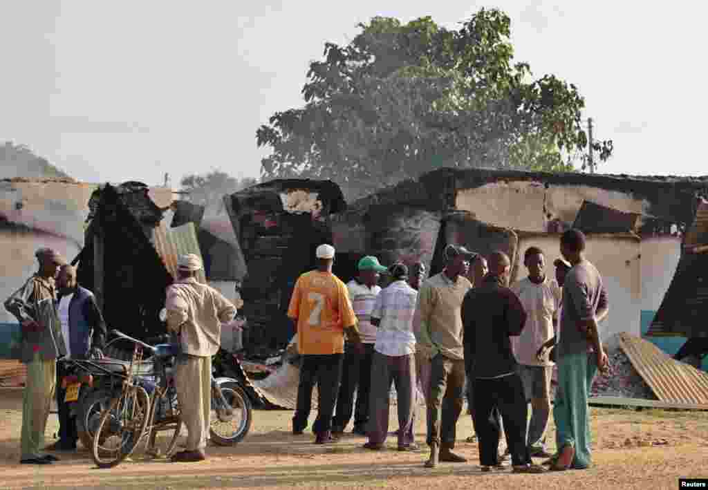 Residents gather behind destroyed structures after gunmen attacked Mpeketoni, Kenya, June 16, 2014. 