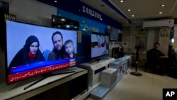 FILE - A Pakistani channel broadcasts a report about the captive U.S.-Canadian couple and their children, seen at a local electronic shop in Islamabad, Pakistan, Oct. 12, 2017.