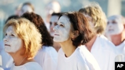 FILE - Demonstrators from the environmental group Greenpeace paint their faces white to highlight coral bleaching in Sydney, Friday, April 22, 2016. 