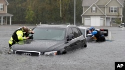 Members of the North Carolina Task Force urban search and rescue team check cars in a flooded neighborhood looking for residents who stayed behind as Florence continues to dump heavy rain in Fayetteville, N.C., Sunday, Sept. 16, 2018.