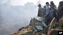 Nepalese rescue workers and civilians gather around the wreckage of a passenger plane that crashed in Pokhara, Nepal, Jan. 15, 2023. 