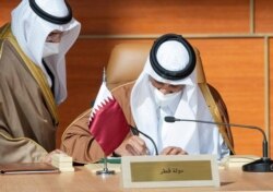 FILE - Qatar's Emir Sheikh Tamim bin Hamad al-Thani signs a document during the Gulf Cooperation Council's summit in al-Ula, Saudi Arabia, Jan. 5, 2021. (Reuters)