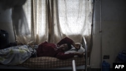 FILE - Mbuh Ronaldo lies in a hospital bed in Buea, the capital of Cameroon's majority English-speaking southwest region, Oct. 4, 2018. Medical doctors are overwhelmed with patients as many of their colleagues seek better pay and working conditions elsewhere. 