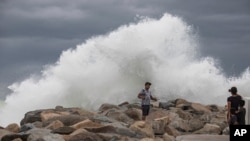 A tourist poses for a photo in front breaking waves before the expected arrival of Hurricane Lorena, in Los Cabos, Mexico, Sept. 20, 2019.