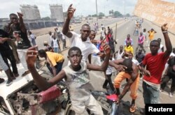 Anti-Gbagbo protesters stand near a roadblock and burning tires in the Abobo area of Abidjan, Ivory Coast, March 3, 2011.