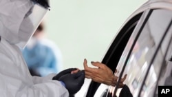 A woman's blood is collected for testing of coronavirus antibodies at a drive through testing site in Hempstead, New York, April 14, 2020. 