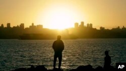 Two men watch as the sun sets over San Francisco from Yerba Buena Island, Jan. 5, 2016.