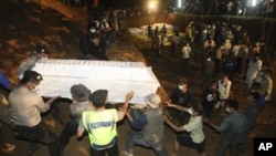 Indonesian volunteers and police carry a coffin at a mass burial site of the victims of the Mount Merapi volcano eruption, 7 November 2010