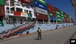 FILE - A Pakistan soldier stands guard while a loaded Chinese ship prepares to depart Gwadar port, about 700 kilometers (435 miles) west of Karachi, Pakistan, Nov. 13, 2016.