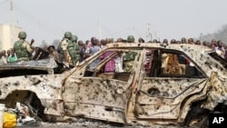 A crowd gathers near a car damaged by an explosion at St. Theresa Catholic Church at Madalla, Suleja, just outside Nigeria's capital Abuja, December 25, 2011.