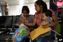 Buena Ventura Martín-Godínez, en el centro, sostiene a su hijo Pedro, a la derecha, mientras ella se reúne con su hija Janne, a la izquierda, en el aeropuerto internacional de Miami, el domingo 1 de julio de 2018 en Miami.