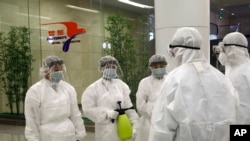 State Commission of Quality Management staff in protective gear and wielding disinfectant prepare to check the health of travelers arriving from abroad at the Pyongyang Airport in Pyongyang, North Korea, Feb. 1, 2020.