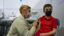 A pediatrician administrates a dose of the Pfizer COVID-19 vaccine to Dimitri Marck, 8 , at the National Velodrome in Saint-Quentin-en-Yvelines, west of Paris, France, Dec. 22, 2021.