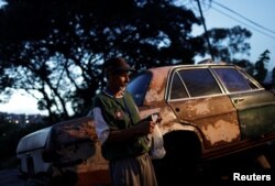 Eduardo Liendo, 63, who lives inside an old car, holds his prize money which he won on "Los Animalitos" (or the Little Animals) betting game on the outskirts of Caracas, Venezuela, October 11, 2017.