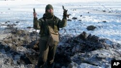 FILE - A Ukrainian soldier shows pieces of shrapnel in a crater left by an explosion in Avdiivka, Ukraine, Jan. 31, 2017.