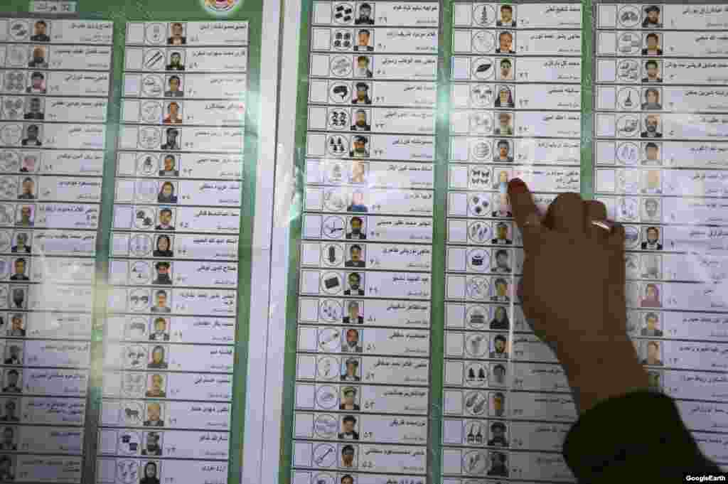An Afghan woman looks for a candidate on a ballot while voting during presidential and provincial elections in Adraskan district, Herat province.