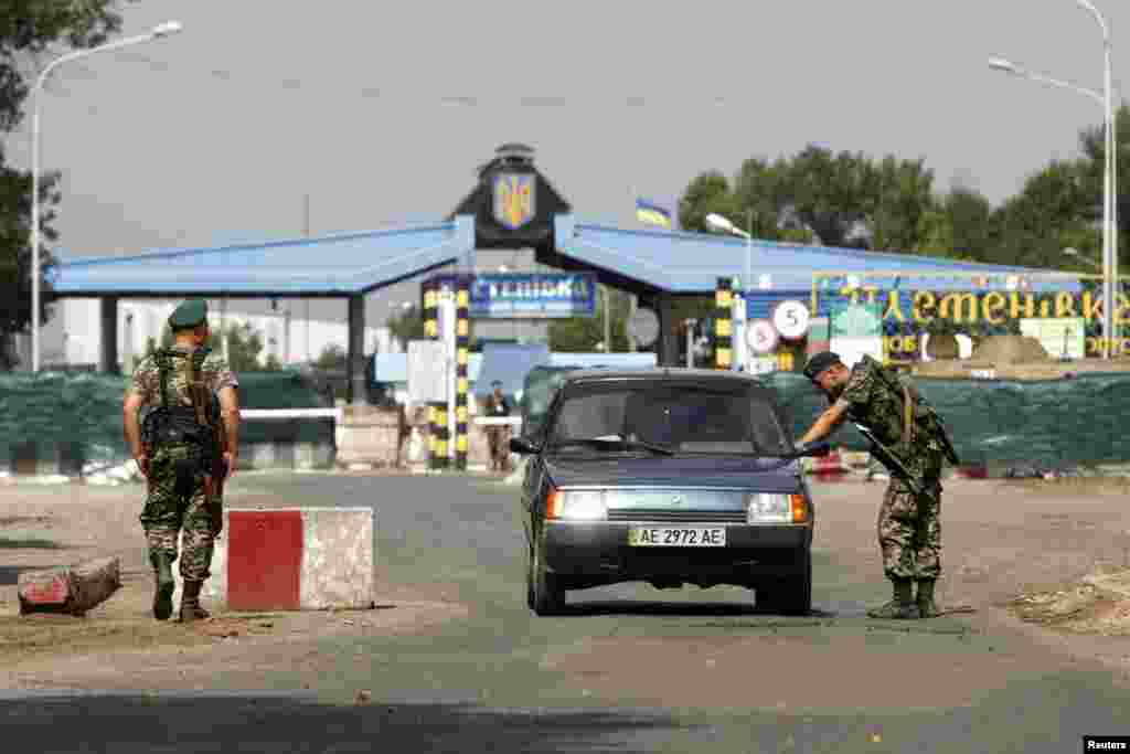 A Ukrainian border guard checks a car at the crossing point Pletenivka, near the border with Russia, in the Kharkiv region, Aug. 13, 2014.