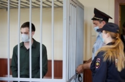 FILE - Former U.S. Marine Trevor Reed stands inside a defendant's cage during a court hearing in Moscow, Russia, July 30, 2020.