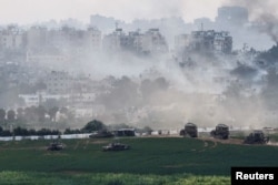 Israeli tanks and other military vehicles maneuver inside the Gaza Strip, as seen from Israel, Oct. 29, 2023.