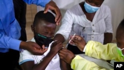 Seorang anak meringis saat menerima vaksin COVID-19 di Diepsloot Township dekat Johannesburg, 21 Oktober 2021.(Foto: AP)