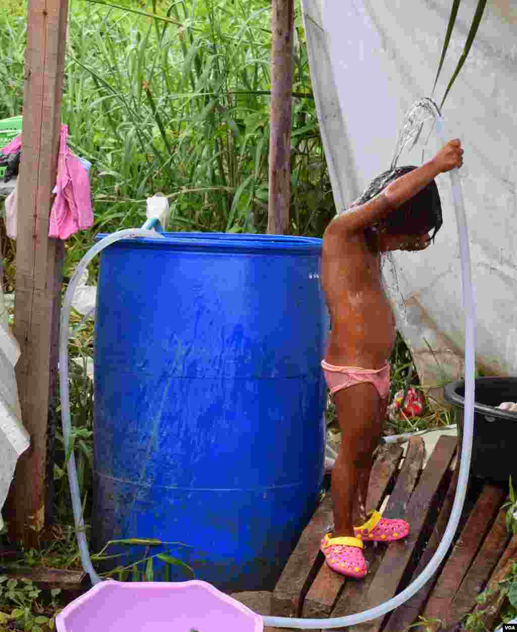 A little girl showers at a construction site, Bangkok, July 10, 2014. (Rosyla Kalden/VOA)