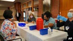 Cristina Licup, kiri, menunggu untuk menerima suntikan booster COVID-19 tempat dia bekerja di Rumah Ibrani di Riverdale di New York, Senin, 27 September 2021. (Foto: AP/Seth Wenig)
