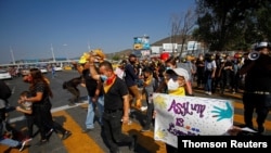 FILE - Migrants and human rights activists protest against U.S. and Mexico immigration policies and for the right to seek asylum, at the San Ysidro border crossing in Tijuana, Oct. 21, 2020.