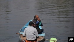 A Kashmiri man talks on his cellphone as he crosses the Dal Lake in Srinagar, Indian controlled Kashmir, Oct. 14, 2019.