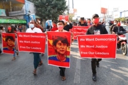 Protesters holding an image of deposed leader Aung San Suu Kyi; President Win Myint in Mandalay, Myanmar on Feb. 8, 2021. A protest against Myanmar's one-week-old military government swelled rapidly Monday morning as opposition to the coup.
