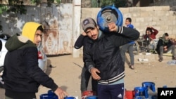 People wait near empty gas canisters to be filled with cooking gas from a tank that entered Gaza via the Rafah crossing with Egypt, in Rafah, Nov. 25, 2023.