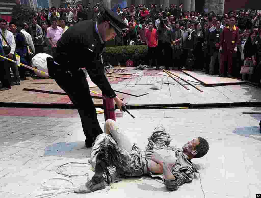 A Chinese police officer (L) talks to a man who tried to self-imolate himself after putting out the fire with a fire extinguisher, along a shopping street in Chongqing. The 41-year-old man is believed to have lost all his money in the ongoing financial cr