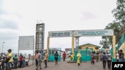 FILE - People walk by the entrance to the Yaounde General Hospital in Yaounde, March 6, 2020, where Cameroon confirmed its first case of COVID-19.