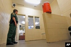 FILE - A Border Patrol agent stands inside one of the holding areas at the Tucson Sector of the U.S. Customs and Border Protection headquarters in Tucson, Ariz., Aug. 9, 2012.