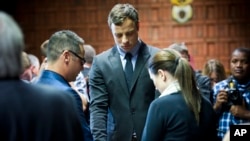 FILE - Oscar Pistorius cries as he prays with his sister Aimee and brother Carl in the magistrates court in Pretoria, South Africa, Aug. 19, 2013. 