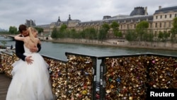 A recently-married couple from Poland, Dominika and Bartek Mieczkowski, embrace near grills covered with "love locks" on a walkway which leads to the Pont de Arts over the River Seine in Paris, France, May 31, 2015. 