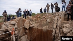 FILE - People watch as Senzo Mchunu, South African police minister (not pictured), inspects outside the mineshaft where it is estimated that illegal miners are believed to be hiding underground, in Stilfontein, Nov. 15, 2024.