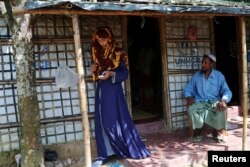 Formin Akter uses her mobile phone as her father Mohammad Hossain watches before she departs for Chittagong to attend school at the Asian University for Women, Aug. 24, 2018.