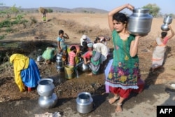 FILE - Indian Lambadi tribal villagers fill drinking water from a leaking pipe on a roadside at Chandampet Mandal in Nalgonda east of Hyderabad on April 25, 2016, in the southern Indian state of Telangana.