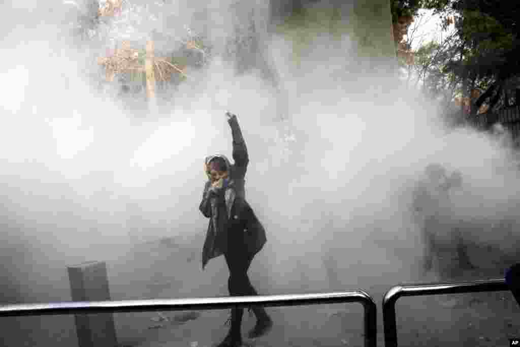 A university student attends a protest inside Tehran University while a smoke grenade is thrown by anti-riot Iranian police, in Tehran, Iran, Dec. 30, 2017. A wave of spontaneous protests over Iran&#39;s weak economy swept into Tehran Saturday, with college students and others chanting against the government just hours after hard-liners held their own rally in support of the clerical establishment.