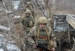 Service members of the Ukrainian armed forces walk on the line of separation from pro-Russian rebels near Donetsk, Ukraine, April 11, 2021.