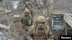 FILE - Service members of the Ukrainian armed forces walk on the line of separation from pro-Russian rebels near Donetsk, Ukraine, April 11, 2021.