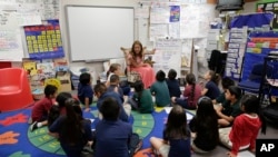 In this Thursday, May 23, 2013 photo, first grade teacher Lisa Cabrera-Terry, center, leads the class in a reading exercise at Jay W. Jeffers Elementary School, in Las Vegas. Eighty three percent of the incoming kindergartners at the school don’t speak En