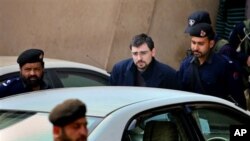 Detained American Aaron Mark DeHaven, wearing glasses, is escorted by Pakistani police officers as he leaves after his court appearance in Peshawar, Pakistan, February 26, 2011