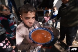 Anak-anak Palestina menerima jatah makanan yang dimasak sebagai bagian dari inisiatif sukarelawan pemuda di Rafah di Jalur Gaza selatan, pada 5 Maret 2024. (Foto: AFP)